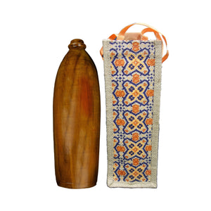 Handcrafted wooden bottle next to a decorative woven jute bag with orange and blue floral patterns